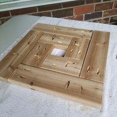 a wooden square with holes in it sitting on a towel next to a brick wall