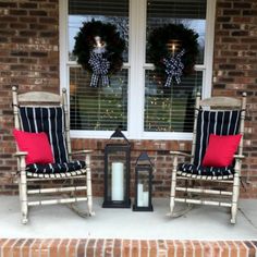 two rocking chairs on the front porch with christmas wreaths in the window behind them