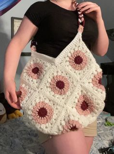 a woman is holding a crocheted bag in her hands