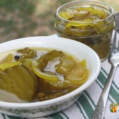 a white bowl filled with pickles next to a jar of pickles on top of a table