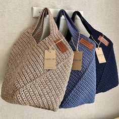 three purses hanging on the wall with price tags attached to them, all in different colors