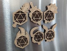 four wooden magnets with different shapes and sizes on a metal surface in front of a metallic background