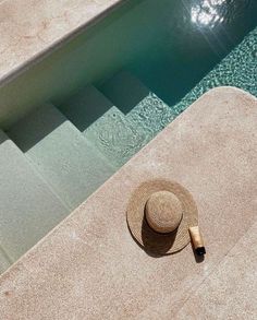 a straw hat sitting on the edge of a swimming pool