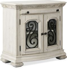 an antique white cabinet with glass doors and scroll designs on the door, side view