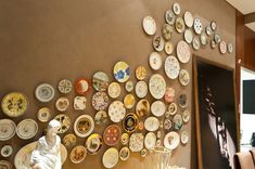 plates are arranged on the wall in front of a table with chairs and vases