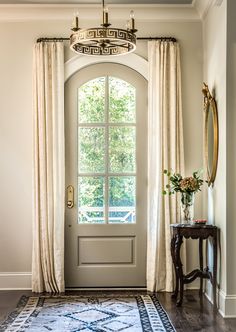 a door is open in front of a window with curtains and a rug on the floor