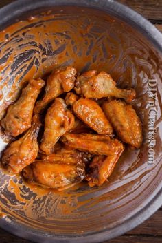 chicken wings with sauce in a bowl on a wooden table