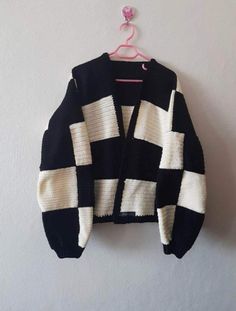 a black and white checkered sweater hanging on a wall next to a pink hanger