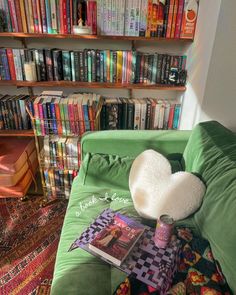 a green couch sitting in front of a book shelf filled with books