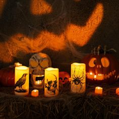 pumpkins and candles lit up in front of a wall with halloween decorations on it