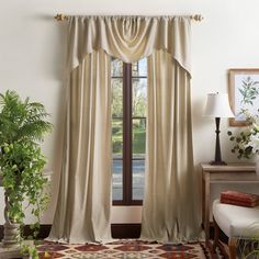 a living room filled with furniture and a large window covered in drapes next to a potted plant