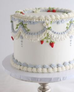 there is a white cake with blue trim on the top and red berries on the bottom