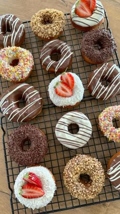 there are many doughnuts on the cooling rack and one is covered with strawberries