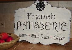 a french patisserie sign sitting on top of a counter next to a bowl of apples