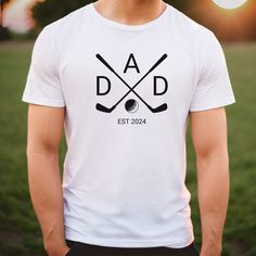 a man wearing a t - shirt that says dad est 2024 with two crossed golf clubs on it