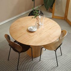 a wooden table with four chairs around it and a potted plant in the corner