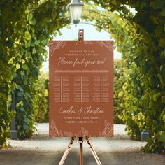 an easel with a wedding seating plan on it in front of some greenery