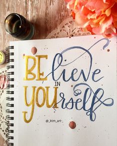 a notebook with the words be believe in yourself written on it next to some flowers