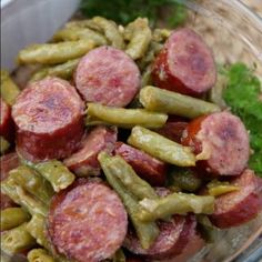 a glass bowl filled with green beans and sausage