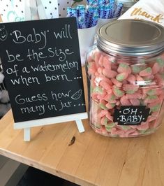 a jar filled with pink and green candy next to a sign that says baby will be the size of a watermelon when born