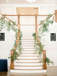 the staircase is decorated with greenery and hanging chandelier for an elegant wedding