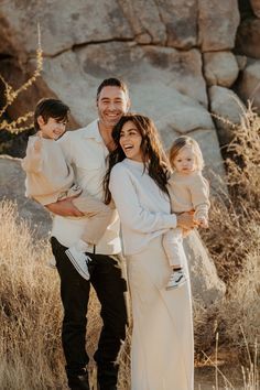 a man, woman and two children posing for a photo in front of some rocks