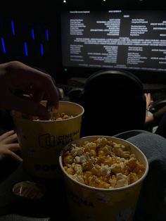 two buckets of popcorn sitting in front of a computer screen with people watching it