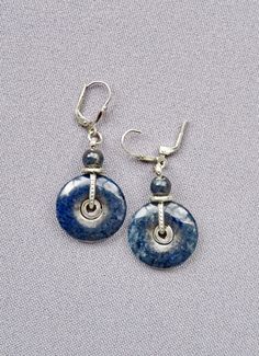 Small donuts made of dark blue and black dumortierite are crafted and handcrafted entirely in sterling silver (925). From centrally placed spirals structured silver wires lead to silver rings and small dumortierite beads up to the lever-backs (= fasteners, see photos 1 + 3), which are perfect for a secure hold.  Each earring is approx. 32 mm long and approx. 20 mm wide - without lever-back (= length approx. 13 mm). >Delivery times from payment: >Germany and EU:  3-8 days, >USA and Canada: 10-20 days, >Norway, Switzerland, UK: 5-10 days, >Australia and other countries: 10-25 days. Note: VAT will not be shown on invoices (§ 19 UStG). Elegant Round Sodalite Jewelry, Blue Spiral Sterling Silver Jewelry, Pierced Lapis Lazuli Round Jewelry, Silver Jewelry With Natural Sodalite Stones, Silver Sodalite Jewelry With Natural Stones, Nickel Free Lapis Lazuli Round Jewelry, 8 Days, Blue And Black, Silver Wire