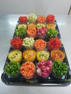 many different types of vegetables are arranged in plastic cups on a tray, ready to be eaten