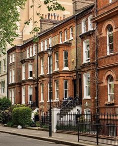 a row of brick townhouses on a street in the city with tall buildings behind them