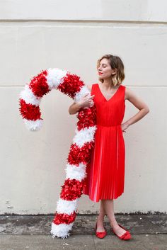 a woman in a red dress is holding a white and red flowered candy cane