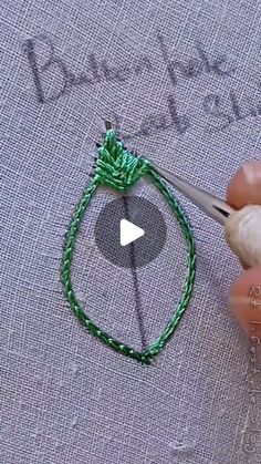 someone is using yarn to make a green bracelet with beads on the end and an arrow in the middle