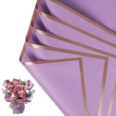 a bouquet of flowers sitting on top of purple paper with gold foil strips around it