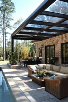 Outdoor patio with a glass roof, wicker furniture, and a pool, surrounded by trees and greenery. Lounge Patio Ideas, Add On Covered Patio, Backyard Patio Designs Pergola, Backyard Decks Ideas, Cover Patio Ideas, Simple Backyard Design, Covered Outdoor Patio Ideas, Covered Pergola Patio, Inside Outside Living