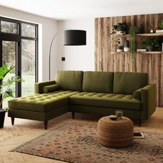 a living room with a large green sectional couch and potted plants on the wall