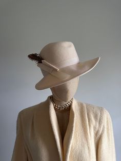 "This striking vintage hat features a face-framing brim; a soft, cream felt body; and an elegant, arching pheasant feather and wool \"bow.\"  Era: 1970s  Label: Peachfelt | 100% wool | Geo W Bollman and Co USA Pictured on a mannequin with a 21 inch head circumference About Geo W Bollman hat company from their website:  * Bollman Hat Company is the oldest hat maker in America, and among the world's oldest because of a stewardship culture and a continuous focus on our innovation, unsurpassed quali Vintage Top Hat With Short Brim For Fall, Vintage Fur Felt Fedora For Fall, Vintage Fedora Top Hat For Fall, Vintage Short Brim Top Hat For Fall, Fitted Hat For Formal Winter Occasions, Vintage Fedora With Curved Brim For Fall, Classic Beige Fedora Felt Hat, Elegant Wool Fedora For Winter, Spring Classic Fitted Felt Hat