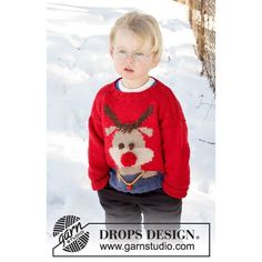 a little boy standing in the snow wearing a reindeer sweater with glasses on his head