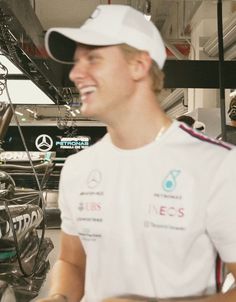 a man wearing a white hat and smiling at someone in front of some equipment on display