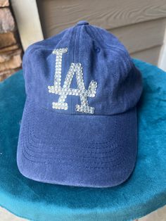 Are you a die-hard LA Dodgers fan looking to elevate your game day outfit? Look no further than our exclusive rhinestone blue washed hat! This stylish cap combines the passion of dodgers baseball with the glamour of rhinestones, making it a must-have for every fan's wardrobe. Crafted with precision and attention to detail, each rhinestone is meticulously placed to highlight the iconic LA logo. Whether you're cheering from the stands, hosting a watch party, or simply running errands around town, Casual Rhinestone Cap, Casual Cap With Rhinestones, Casual Snapback Baseball Cap With Rhinestones, Casual Adjustable Baseball Cap With Rhinestones, Casual Rhinestone Snapback Hat, Casual Rhinestone Hat, One Size, Casual Rhinestone Hat, One Size Fits Most, Casual Rhinestone Hat One Size Fits Most, Casual Rhinestone Hat