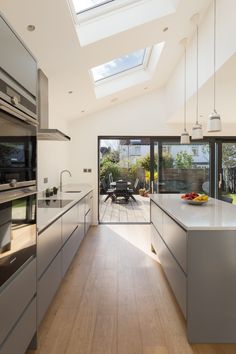 an open kitchen with skylights and stainless steel appliances on the counter tops, along with wooden flooring