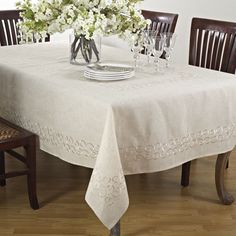 a dining room table with white flowers in a vase