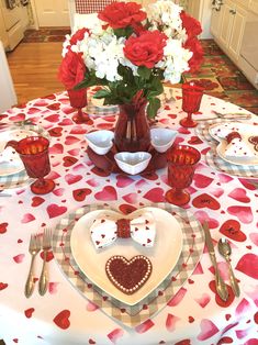 the table is set for valentine's day with red and white flowers