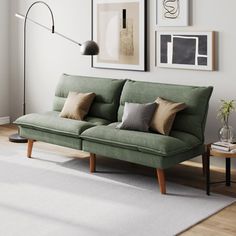 a living room with a green couch and two pictures on the wall above it, along with a white rug