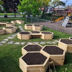 a group of wooden planters filled with dirt on top of a grass covered field