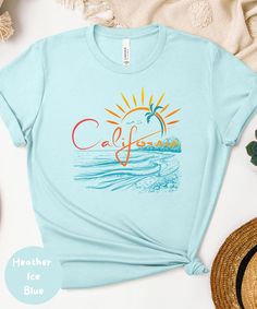 * D E S C R I P T I O N  * ✺ Embrace the laid-back vibes of the West Coast with our stylish summer t-shirt! Featuring the word "California" in a playful, fun font, this tee captures the essence of endless summer days. Behind the word, a setting sun creates a stunning backdrop, with colors that blend seamlessly into a beautiful gradient of a summer sunset. Whether you're hitting the beach or enjoying a warm evening out, this t-shirt is the perfect way to carry a piece of California sunshine with you wherever you go. * S H I P P I N G * T I M E S * ✺ My items are individually made for each of you. Because of this, my processing time is 2-7 business days (depending on order volume) plus transit time, but typically much faster. I know you want your items as quickly as possible! * H O W * T O * Summer Vacation Tops With Palm Tree Print, Summer Tops With Palm Tree Print For Vacation, Beach Season Tops With Screen Print For Summer Adventures, Blue Palm Tree Print Tops For Beach Season, Summer Tops With Palm Tree Print For Beach Season, Blue Palm Tree Print Summer Tops, Palm Tree Print Summer Tops For Beach Season, Blue Palm Tree Print Tops For Summer, Trendy Printed Shirt For Beach Season