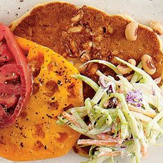 two tacos and a salad on a white plate with some nuts in the background