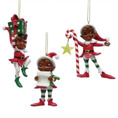 three christmas ornaments hanging from strings on a white background, one is holding a sign and the other has a candy cane