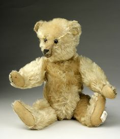 a brown teddy bear sitting on top of a white floor next to a gray background