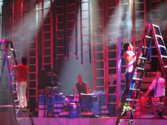 a group of people standing on top of a stage next to a set of ladders