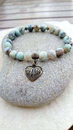 A gentle energy emanates from this "Connection" bracelet in aqua terra jasper. It will help you keep a positive state of mind, regain hope if you no longer have any, it will bring you peace, harmony and a feeling of compassion for others and for yourself. Composed of 21 aqua terra jasper beads, decorated with small bronze-colored metal beads and a pretty heart-shaped "love" medal. Dimensions: approximately 18 cm (can be adjusted on request, other sizes possible on order) Because you are unique, Bohemian Jasper Bracelets As A Gift, Earthy Amazonite Jewelry For Gifts, Earthy Amazonite Jewelry Gift, Bronze Bracelets With Natural Stones For Gift, Spiritual Jasper Beaded Bracelets As Gift, Spiritual Bronze Bracelet For Gifts, Releasing Negative Energy, Pretty Heart, Aqua Terra